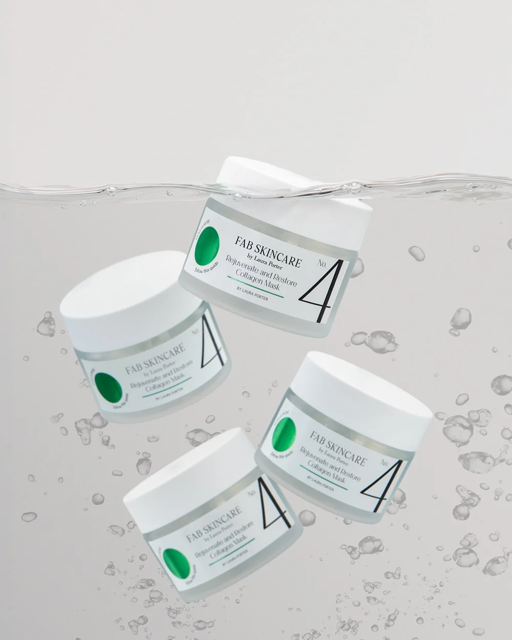 Product Hero photography shot showing Four white jars of FAB Skincare Collagen Mask floating underwater with bubbles around product photography by roy mccready photography