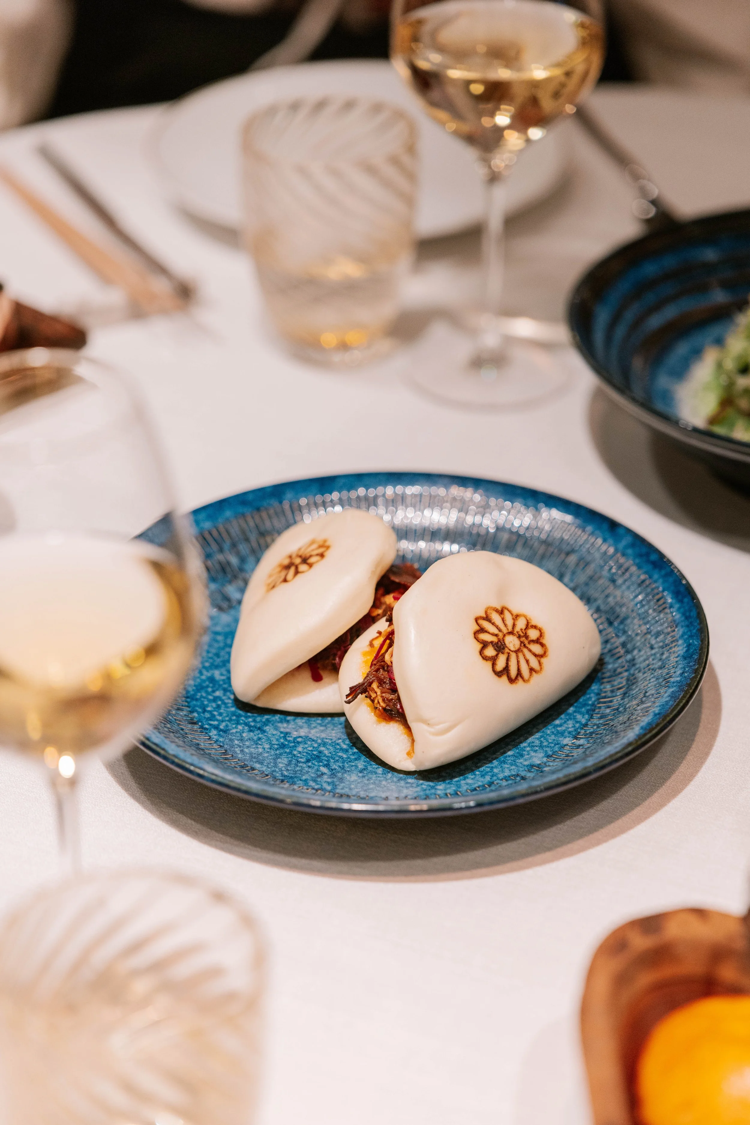 A white tablecloth with various dishes and wine glasses.