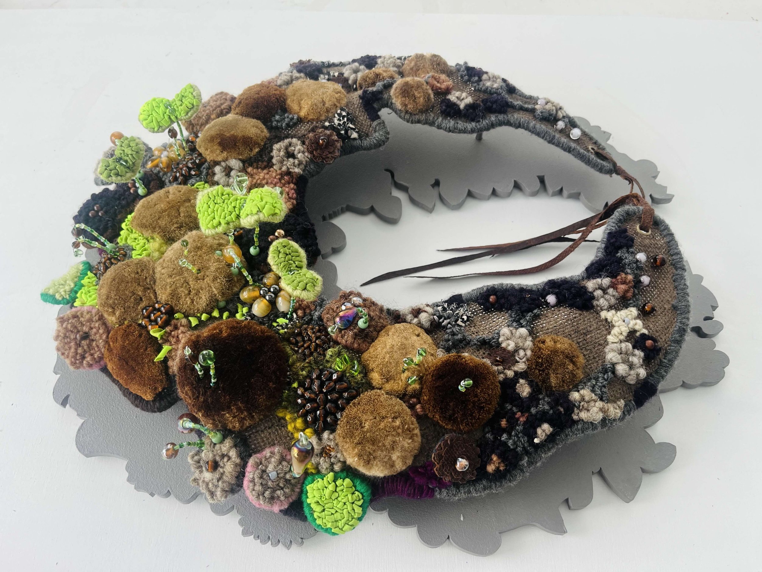 Seedwork Rising 15 W x 18 H x 4 D ",  Repurposed and metallic textiles, yarn, fish leather, cattail seeds, beads, clay $750