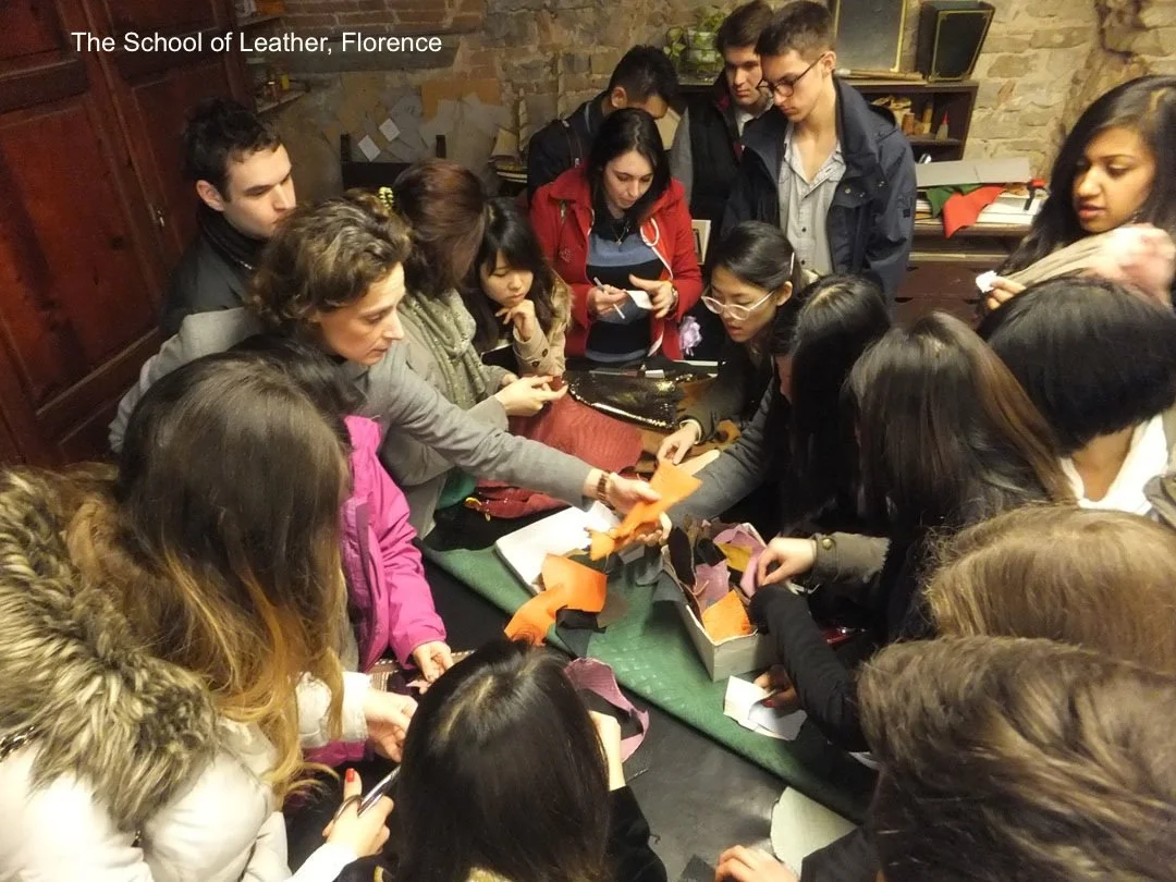 Students gathered around a worktable at the School of Leather in Florence, watching a demonstration