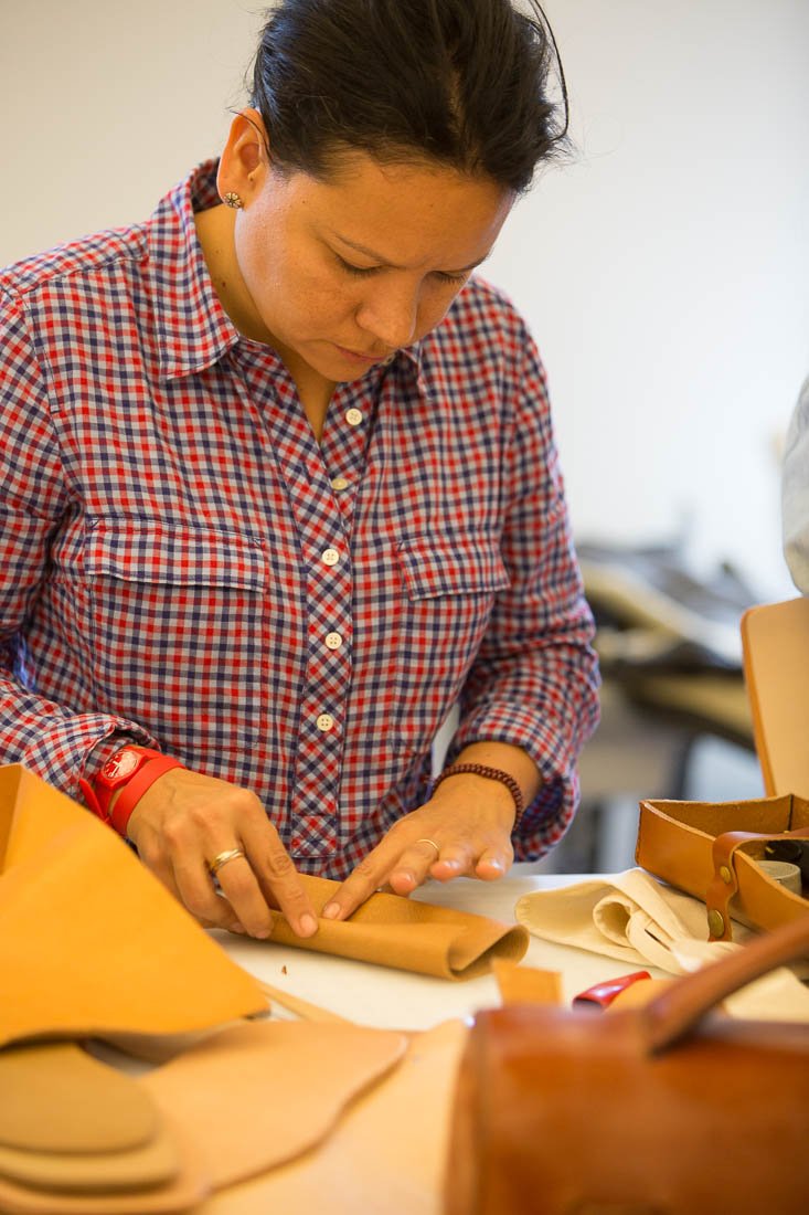 A participant cutting leather pattern pieces at a workshop table