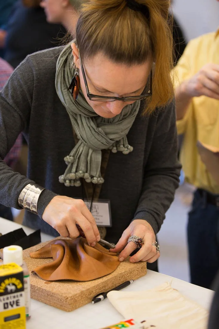 A workshop participant shaping a piece of leather by hand at the bench
