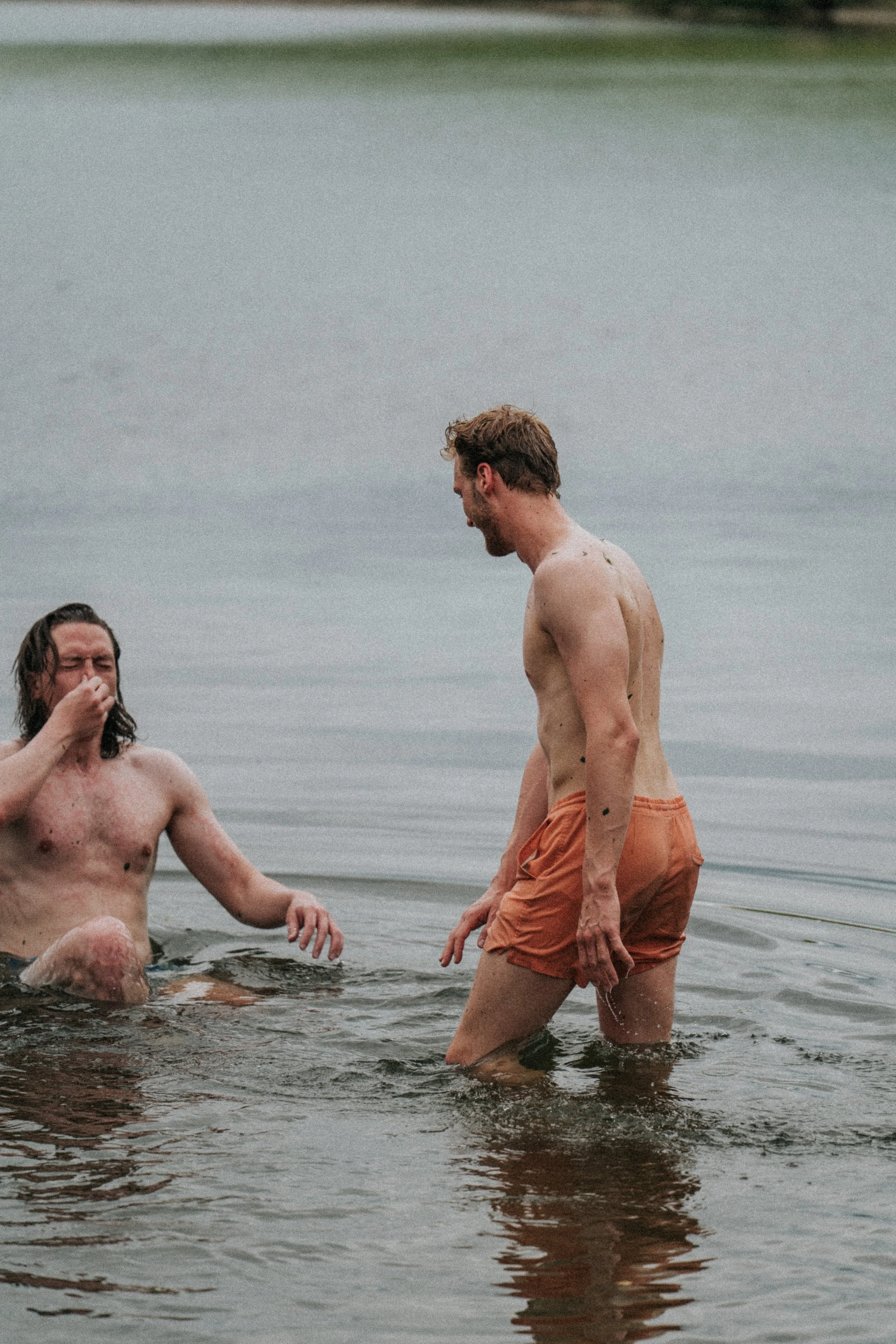 Två män i vatten, den ena jätte, den andra puslar med korta badbyxor.