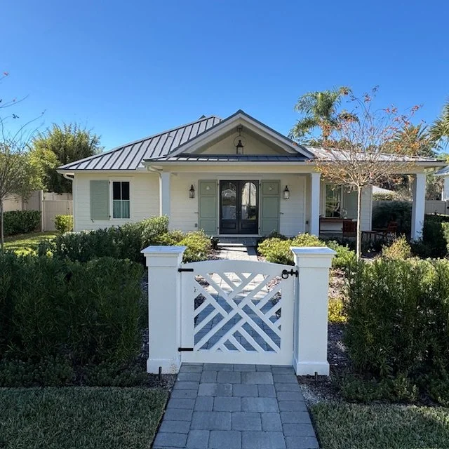 Riverfront cottage-style home in Palm Valley, Ponte Vedra Beach, Florida featuring custom exterior shutters, white siding, and a landscaped entry with garden gate.