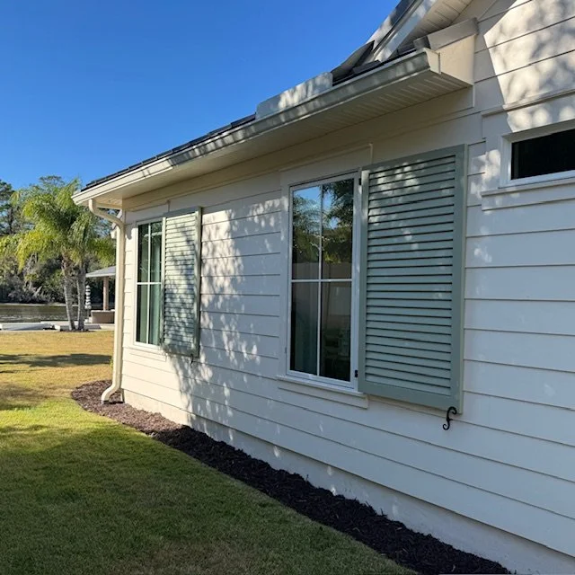 Riverfront Palm Valley home in Ponte Vedra Beach, Florida featuring custom exterior shutters, white siding, and a coastal cottage design with garden entry gate.