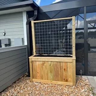 “Custom cedar planter box with galvanized wire trellis installed at a home in Nocatee, Florida, designed for climbing plants and compact garden spaces.”