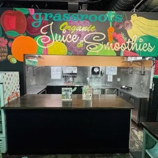 Custom-built coffee and juice bar installed inside Grassroots Natural Food Store in Five Points, Jacksonville, Florida, featuring a wood countertop and black service front.