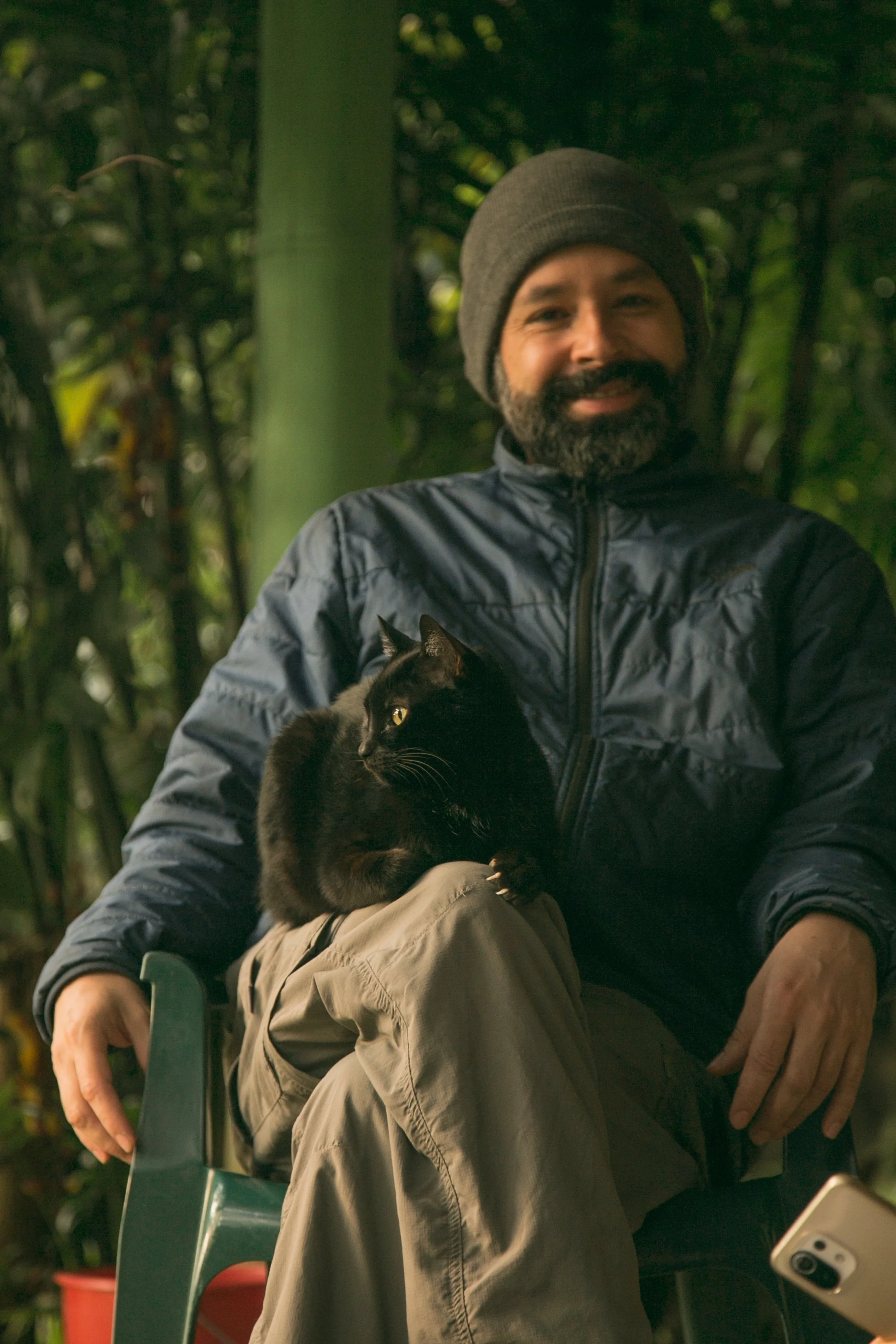Andrés seated in the forest at Kaukitá with one of his cats.