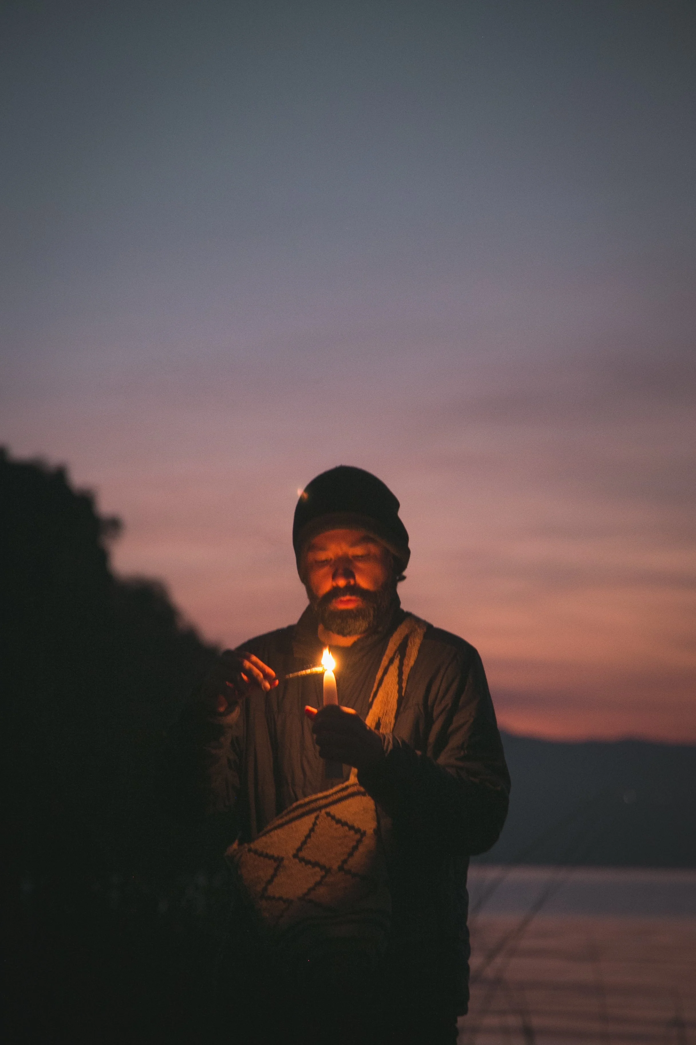 Andrés lighting a candle at dusk.