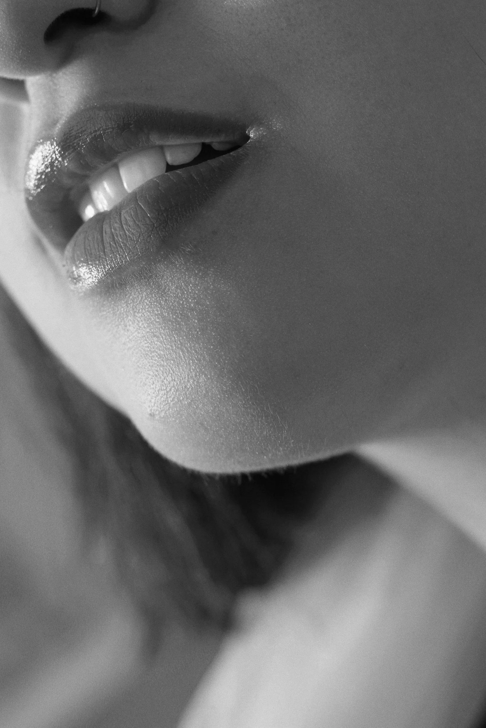 Close-up black and white photo of a woman's parted lips, showing her upper teeth.