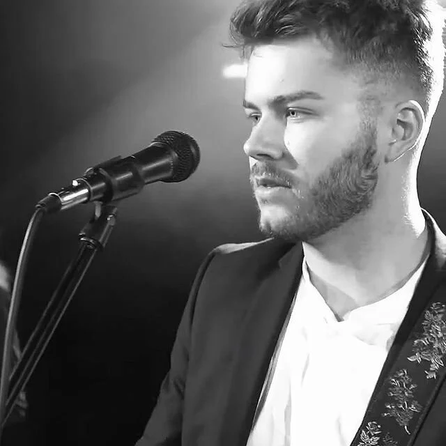 Lewis Corbett Guitar Teacher in front of a microphone.