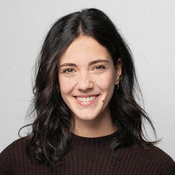 Saramina Ehlert, Werkstudentin, Praxismanagement, lächelnd, dunkle, gewellte Haare, trägt Ohrringe und braunen Wollpullover.