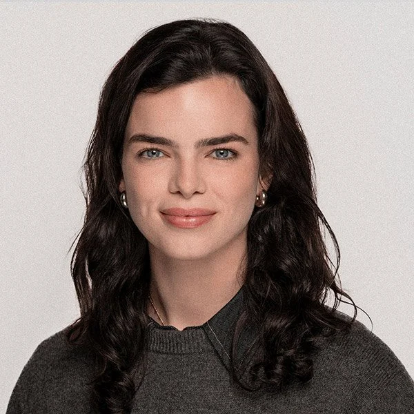 Emilia Solms, Psychologin, freundlich zugewandt, lange braune Haare, trägt Ohrringe und graues Hemd mit grauem Pullover.