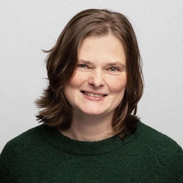 Michaela Waldbauer, Termin- und Praxismanagement, lächelnd, schulterlanges Haar, trägt grünen Woll Pullover.