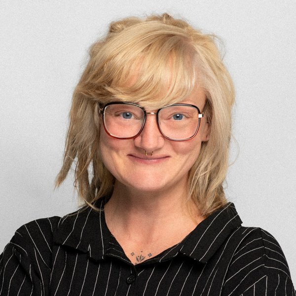 Julia Praefke, Psychologin, lächelnd, kurzes blondes Haar, trägt Brille und schwarze Bluse mit weißen Streifen.