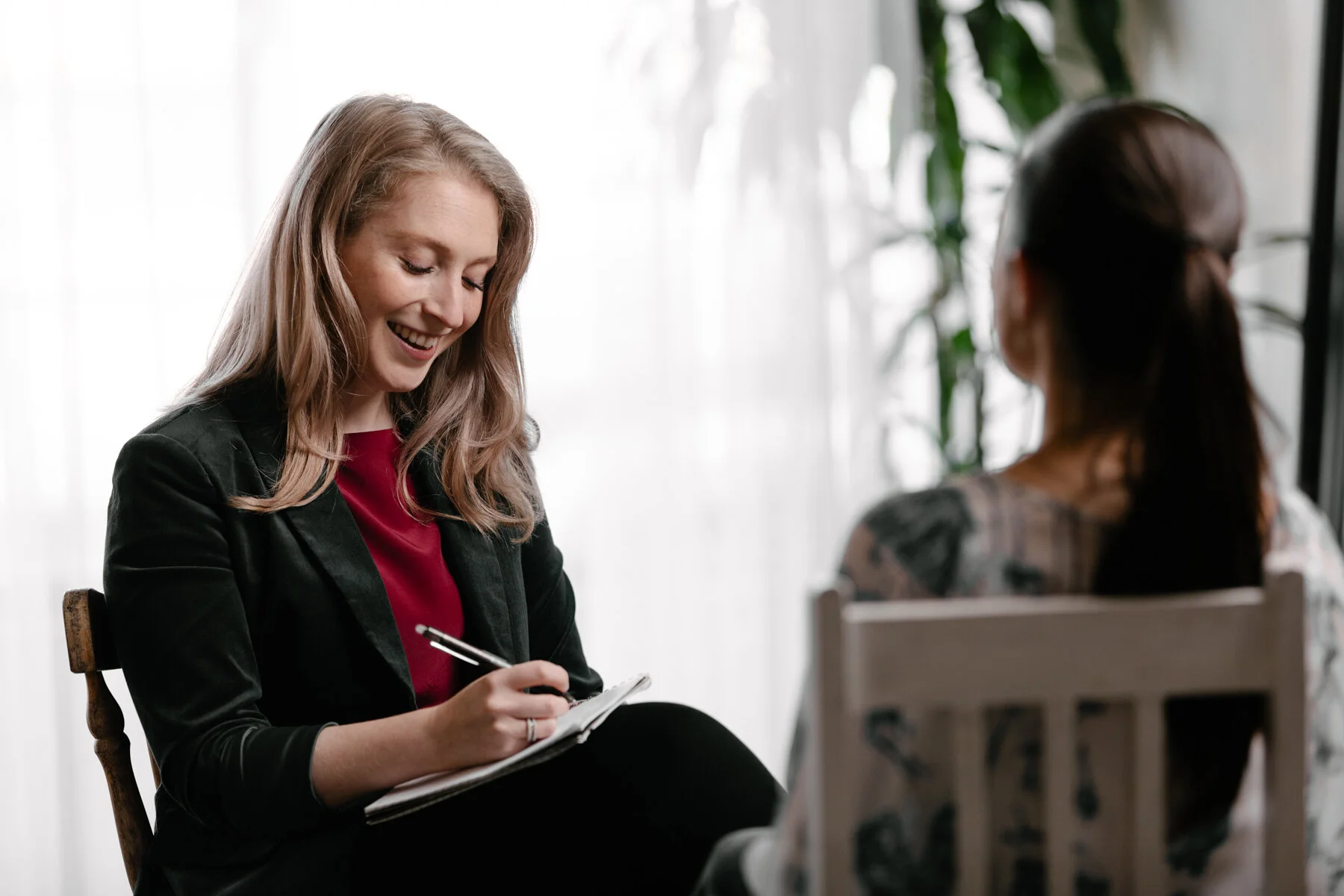 Clinical psychologist taking notes and smiling during a therapy session with a client in Melbourne