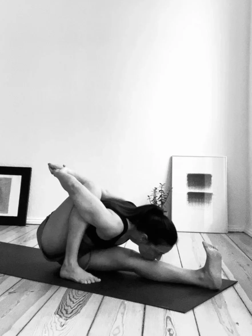 Private Yoga teacher Katharina Fengler demonstrating Marichyasana A from Ashtanga Yoga Primary Series in Berlin apartment in front of abstract art. 