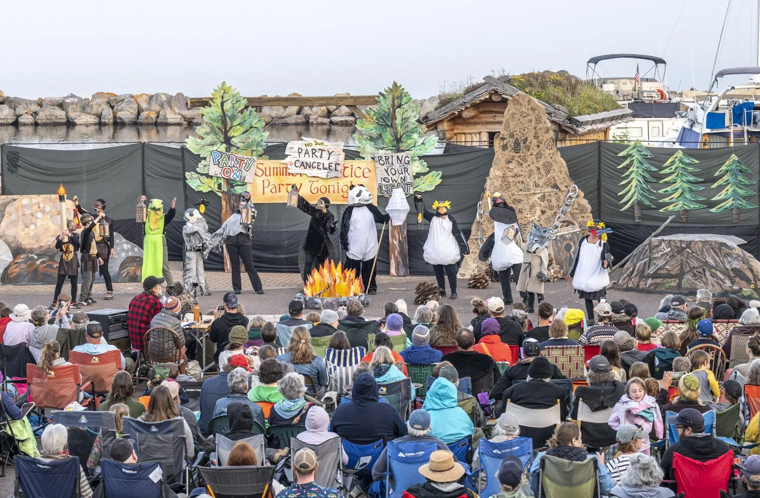 Image of a large puppet show featuring people dressed as various animals in the forest.