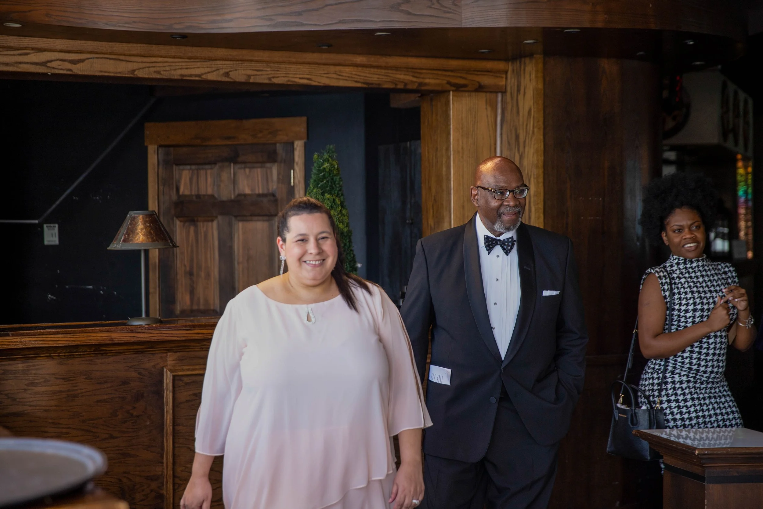 People attending a formal event in a restaurant or banquet hall, with wooden interior decor.