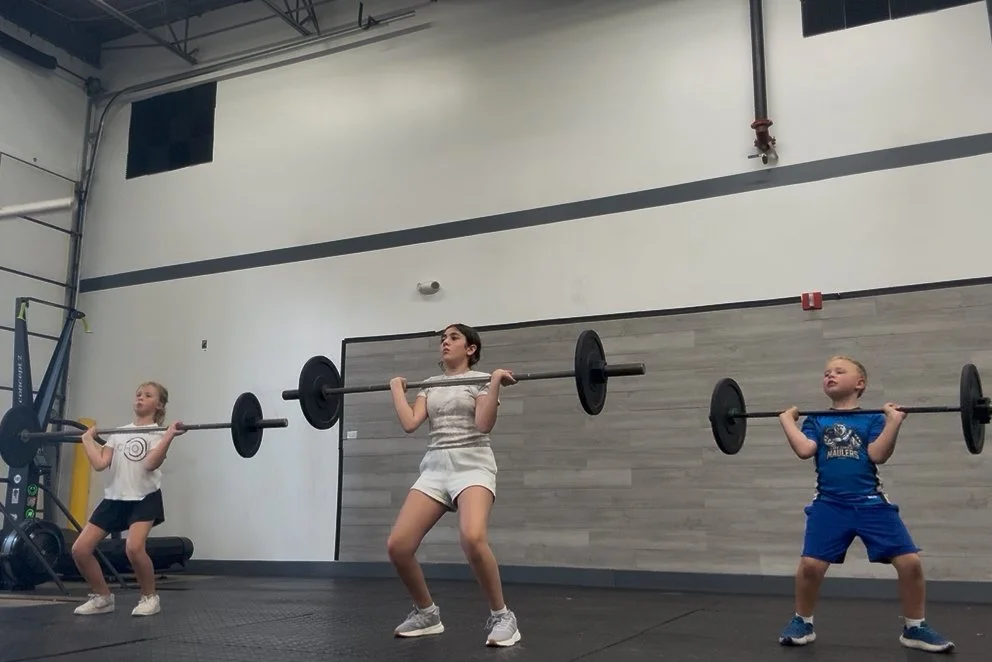 Kids working out with CrossFit barbells