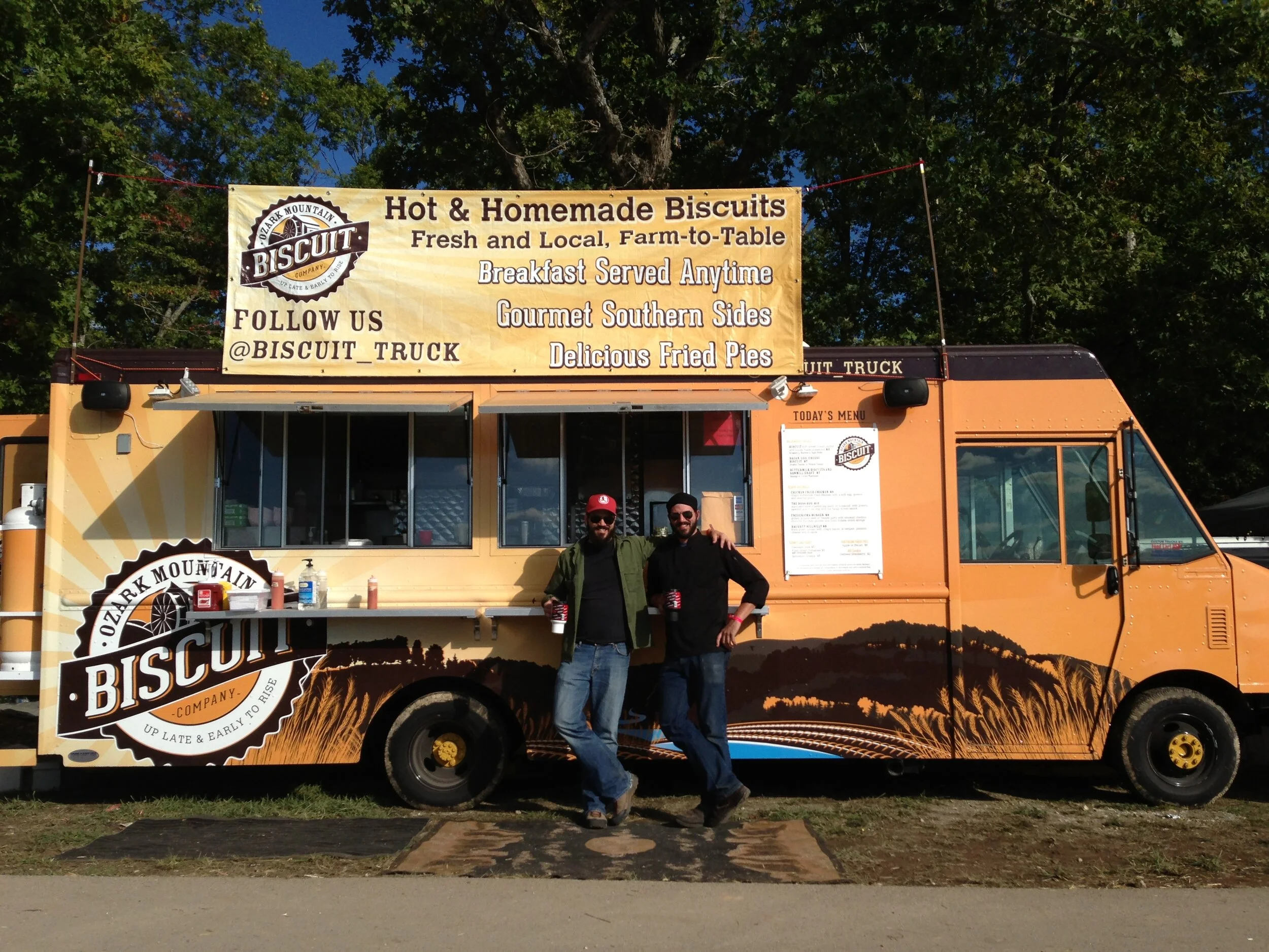 Two customers stand in front of the Ozark Mountain Biscuit food truck.