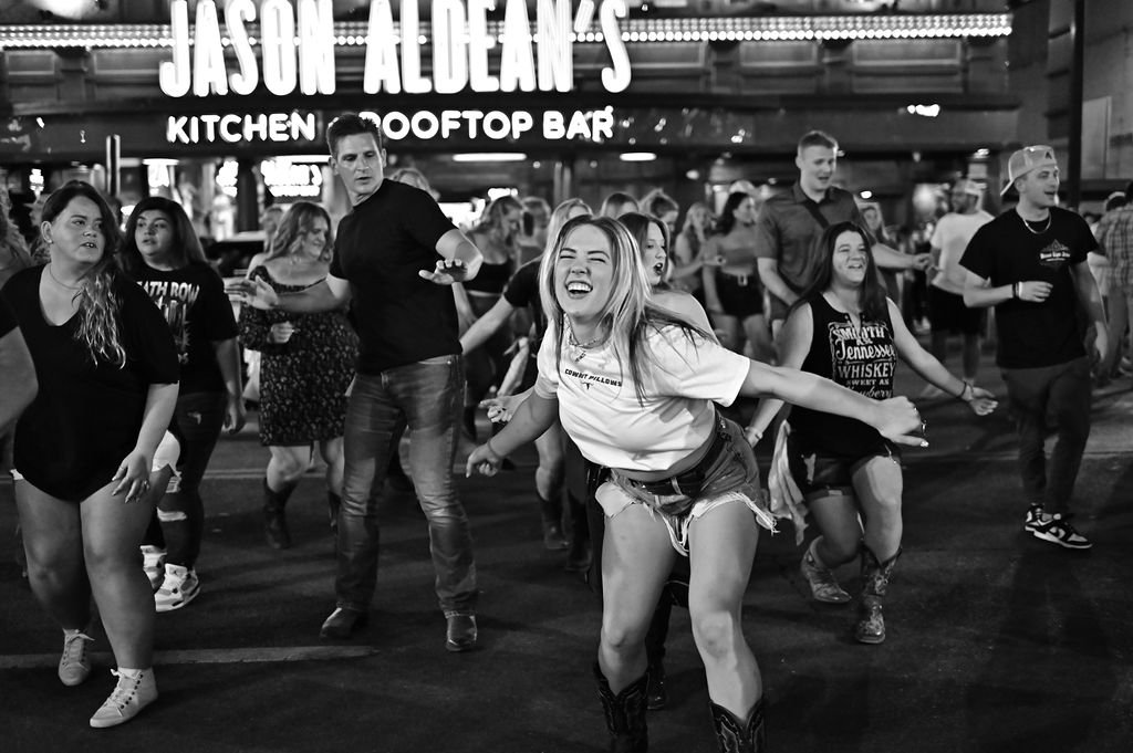 People dancing and having fun outside Jason Aldean's Kitchen & Rooftop Bar at night.