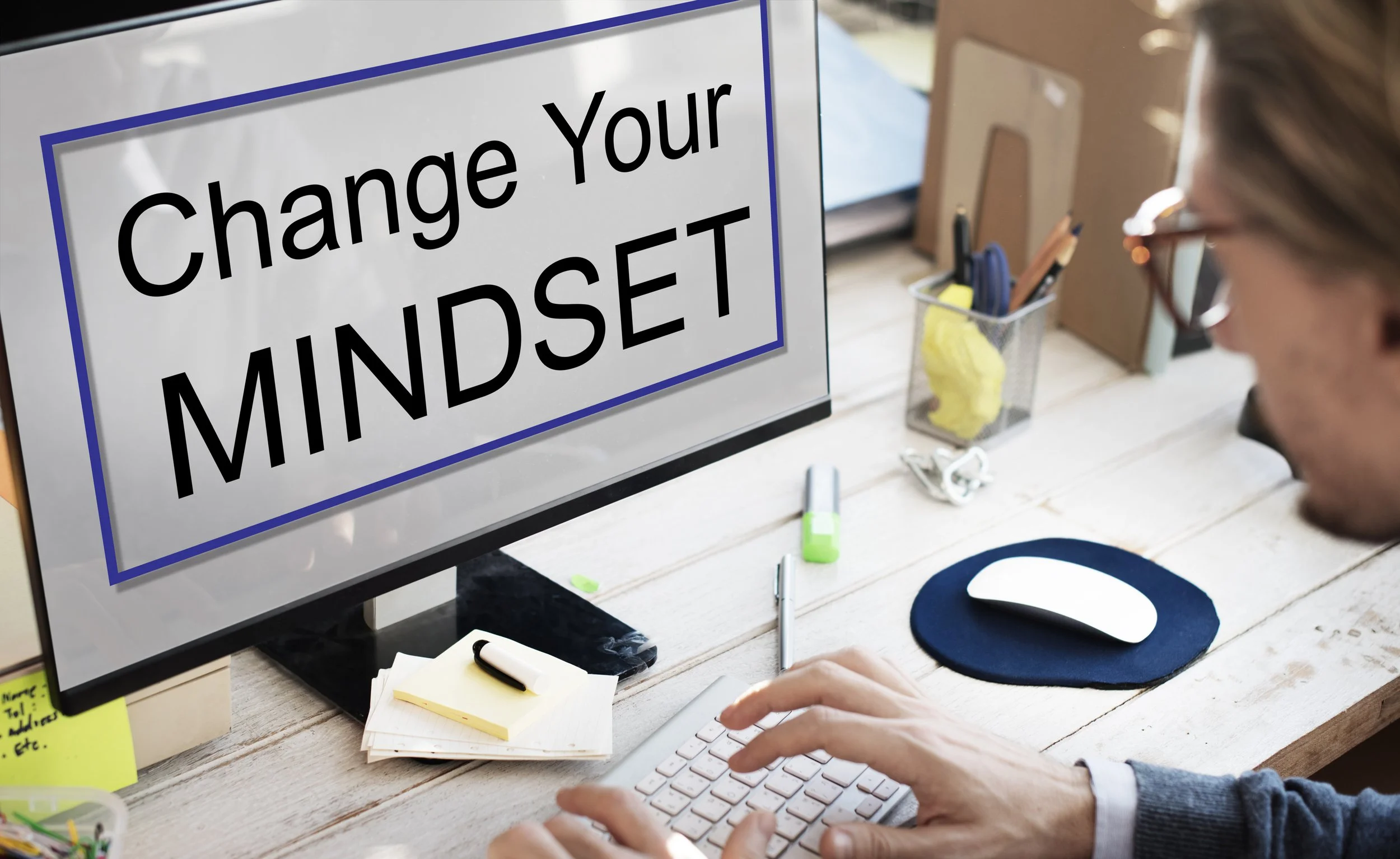Woman seated at a desk looks at computer monitor that says Change Your Mindset