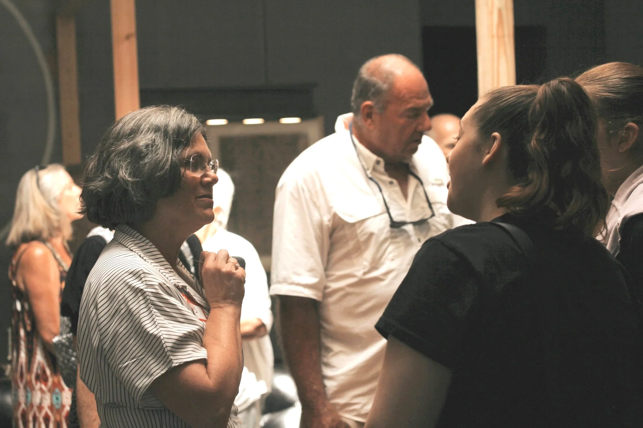 Group of people engaged in conversation at an indoor event or gathering.