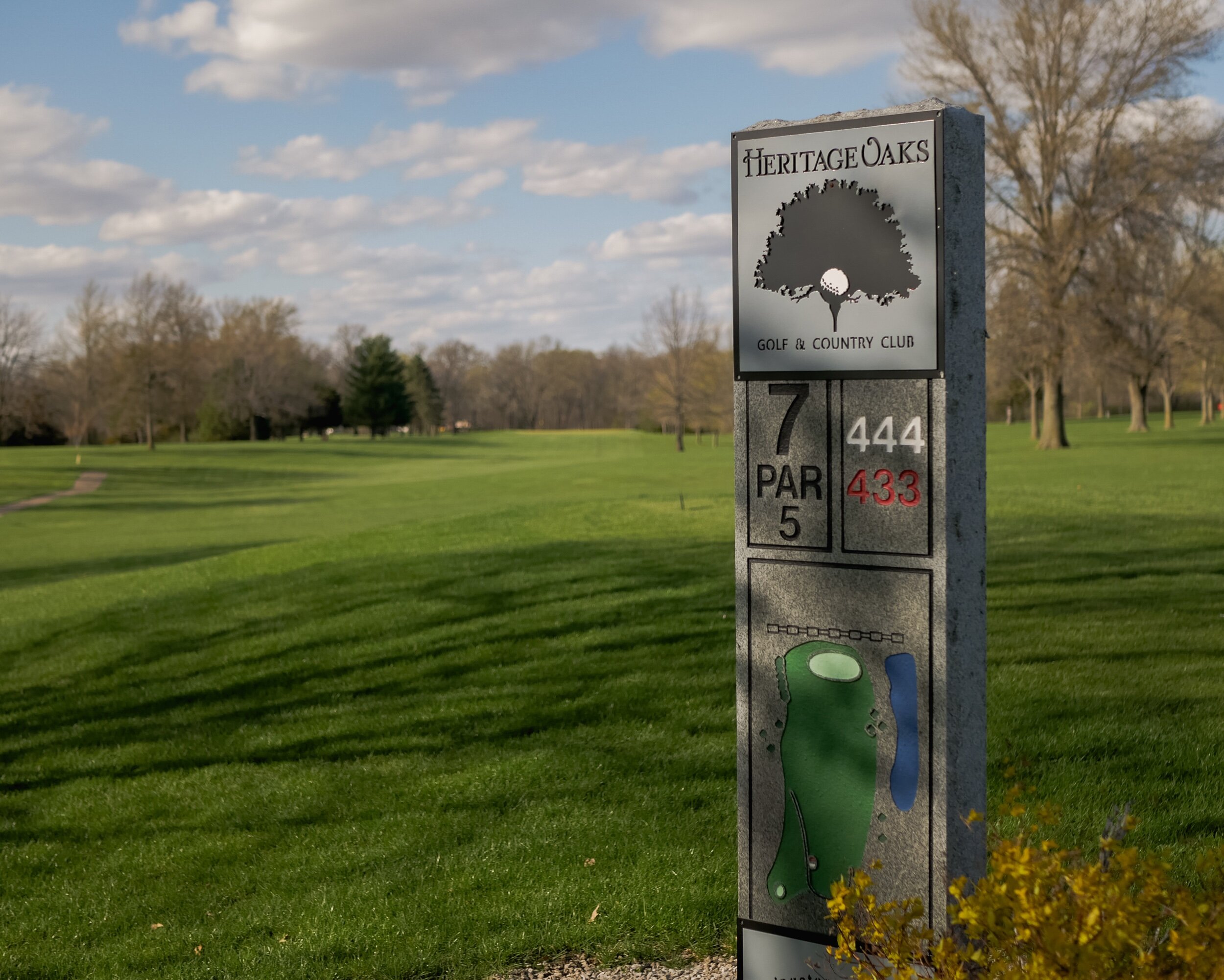 golf hole tee marker with yardages for each tee and a drawing of the hole on stone