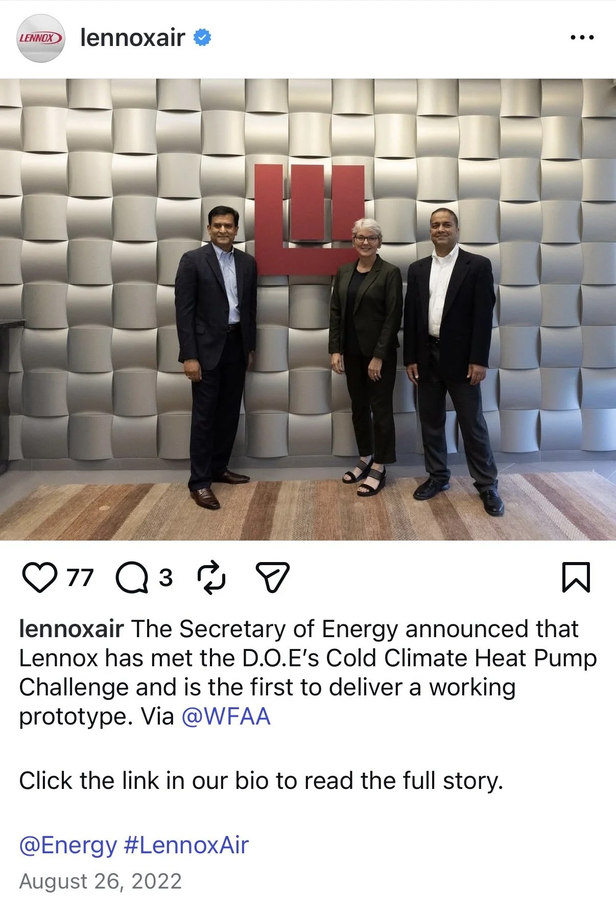 Three people in business attire standing in front of a textured wall with a large red logo for Lennox.