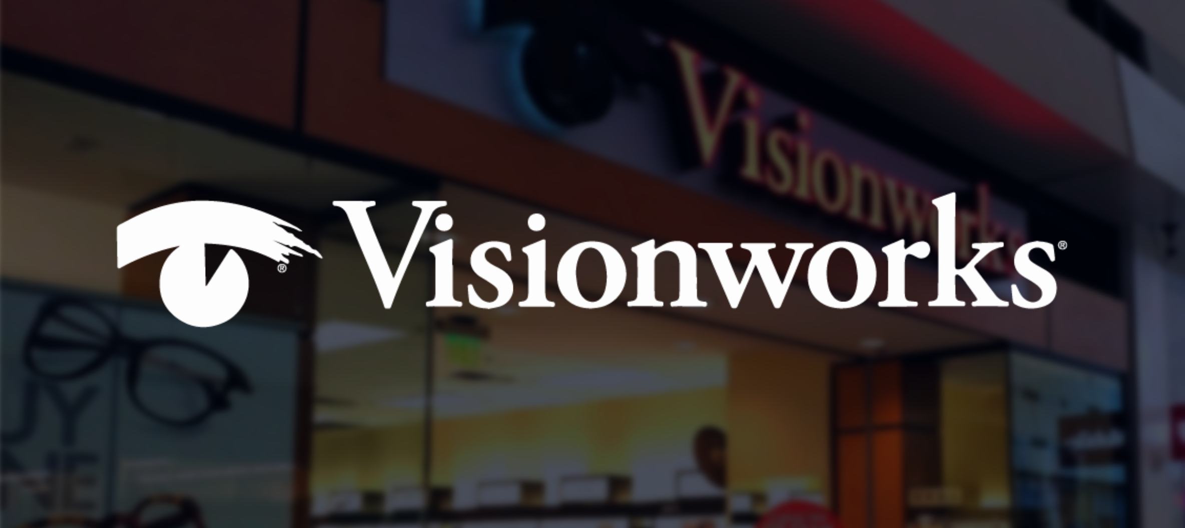 Visionworks store signage with logo in the foreground, background shows part of the store interior and display.