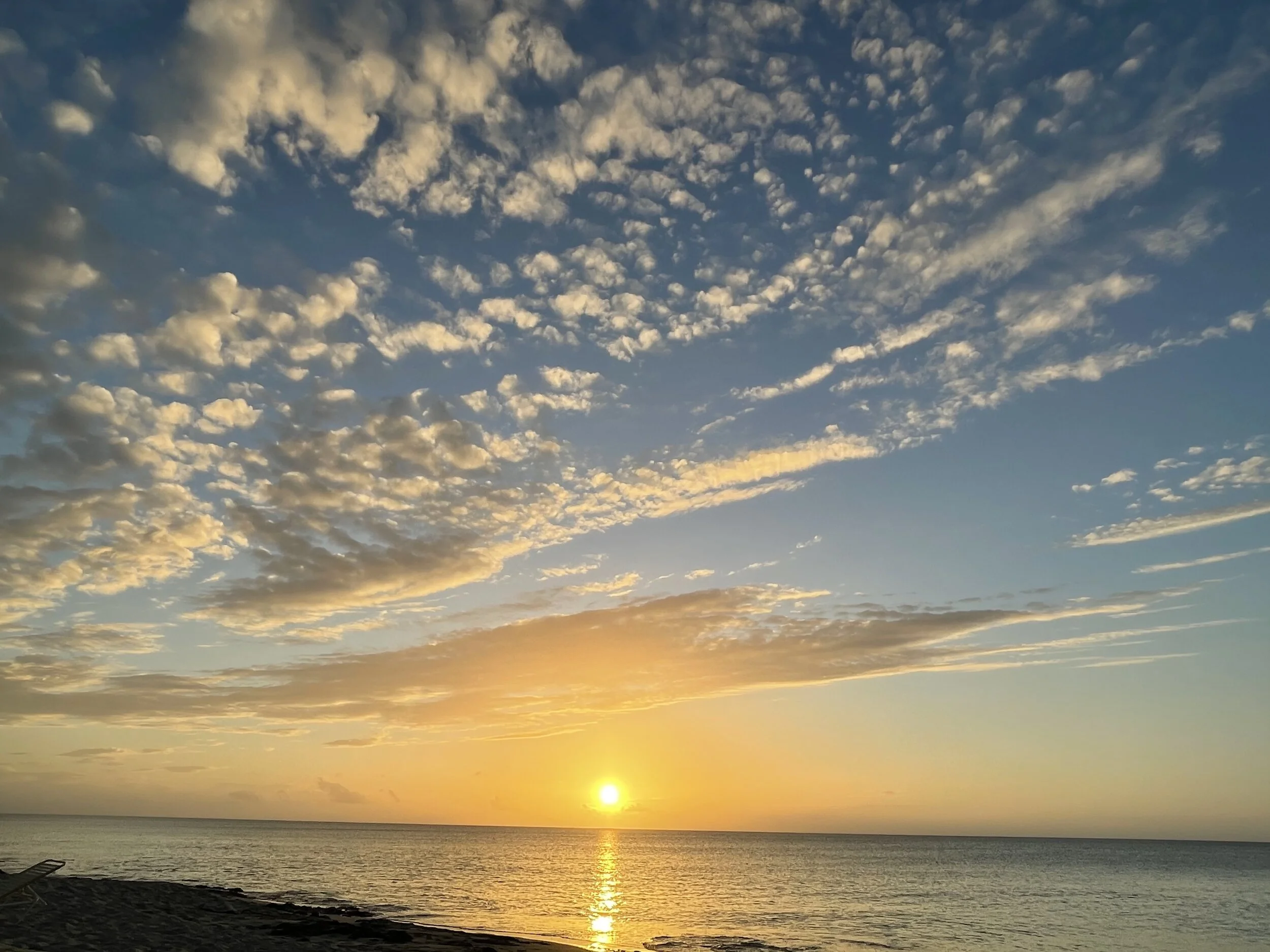 Sunset over ocean with scattered clouds and calm waters