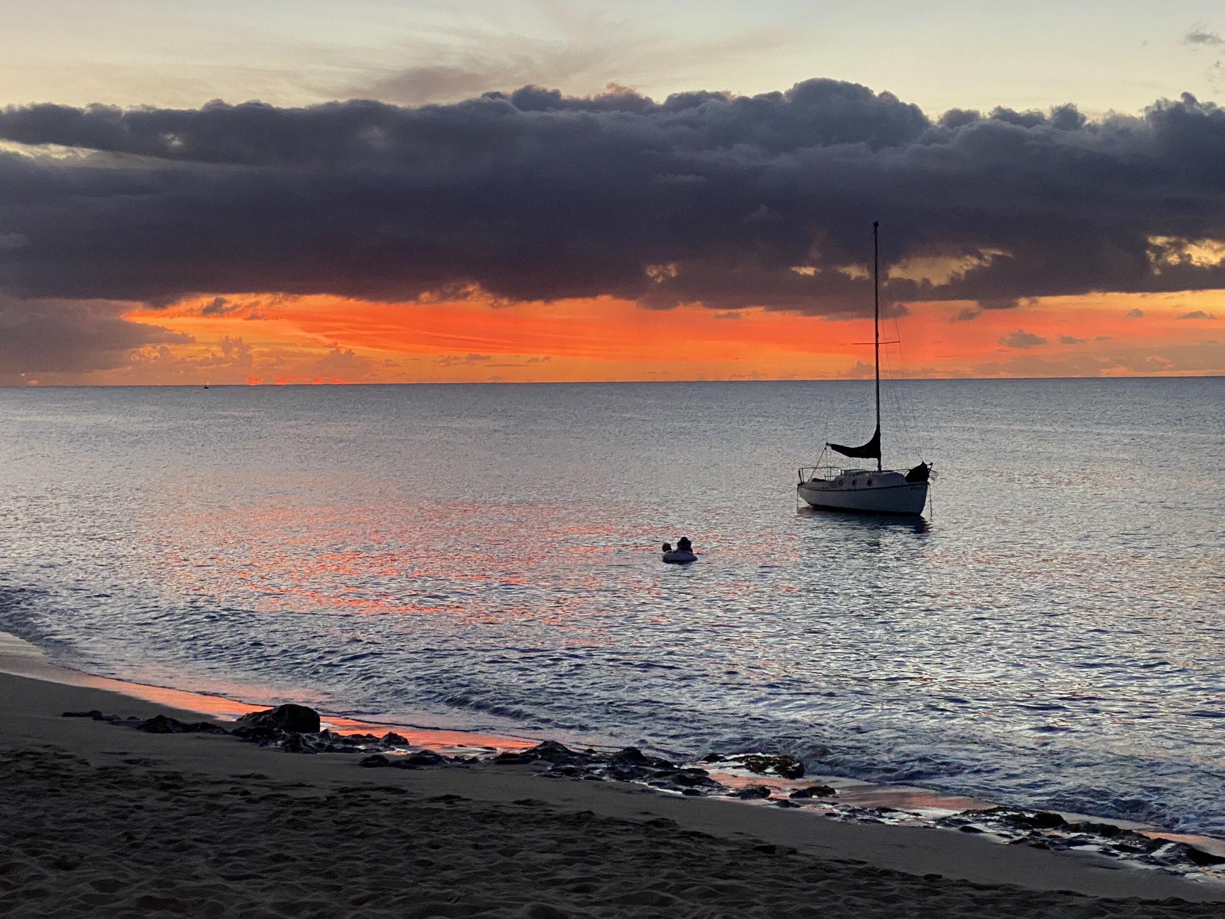 Sailboat on ocean at sunset with dramatic clouds