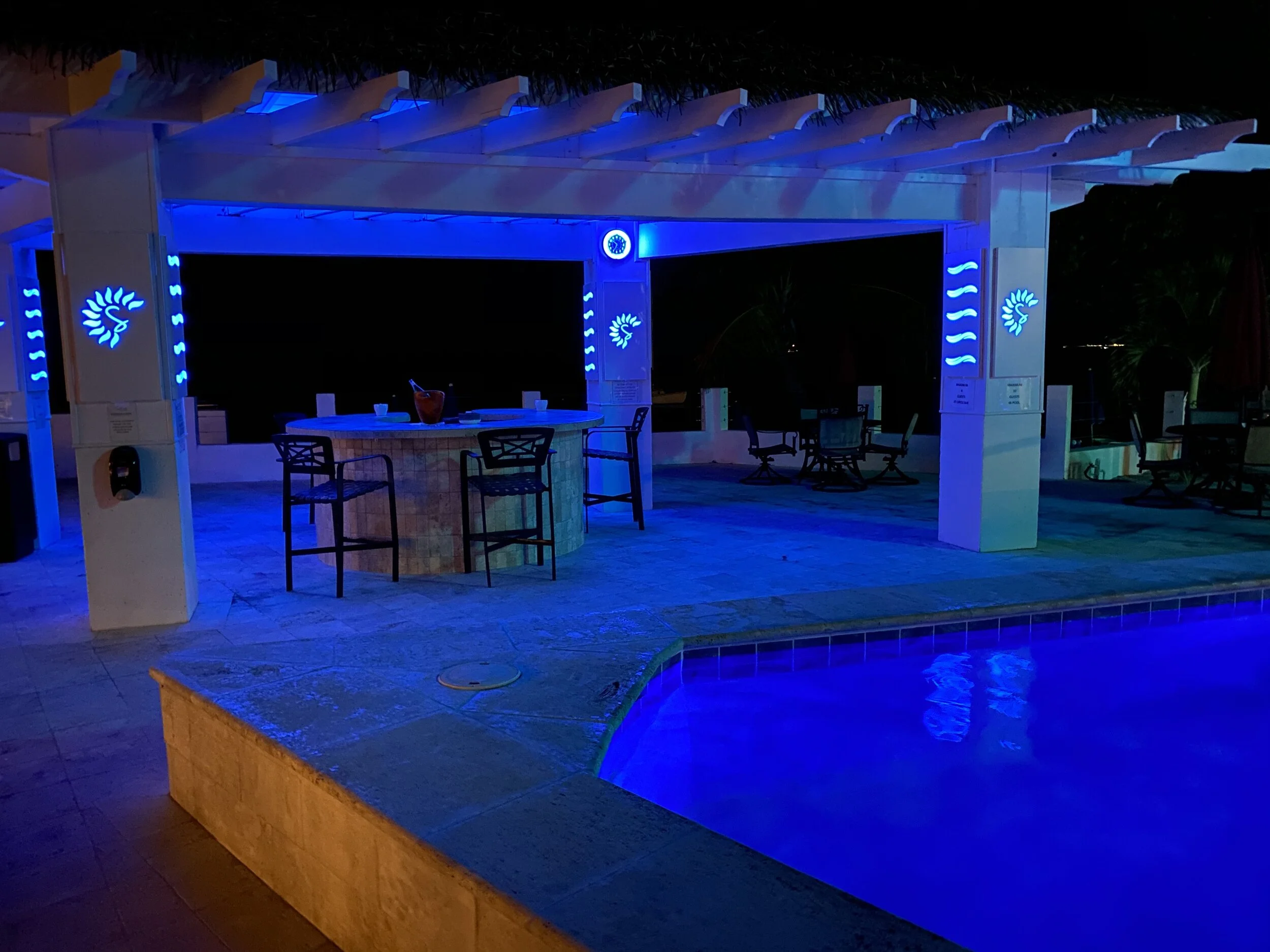 Outdoor bar area with blue lighting by a pool