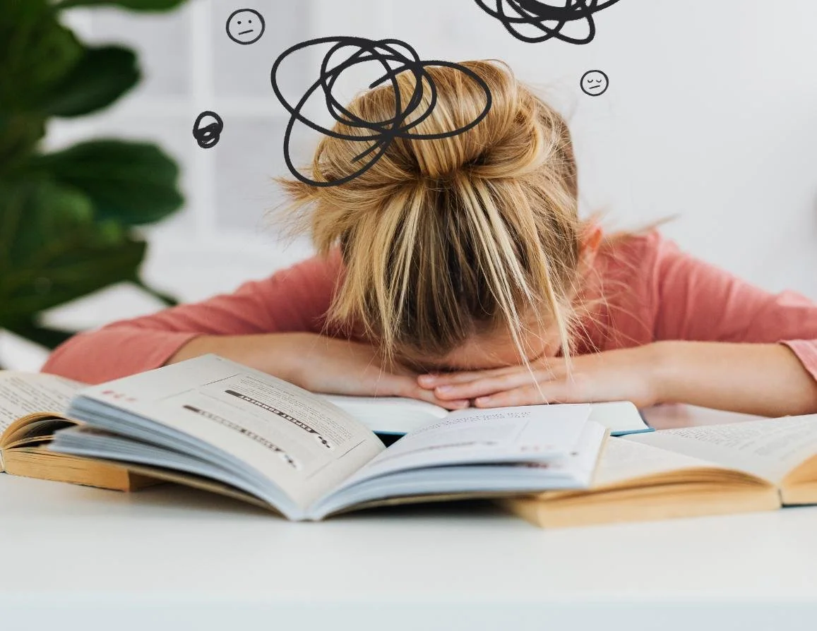Blonde woman with head on desk looking overwhelmed
