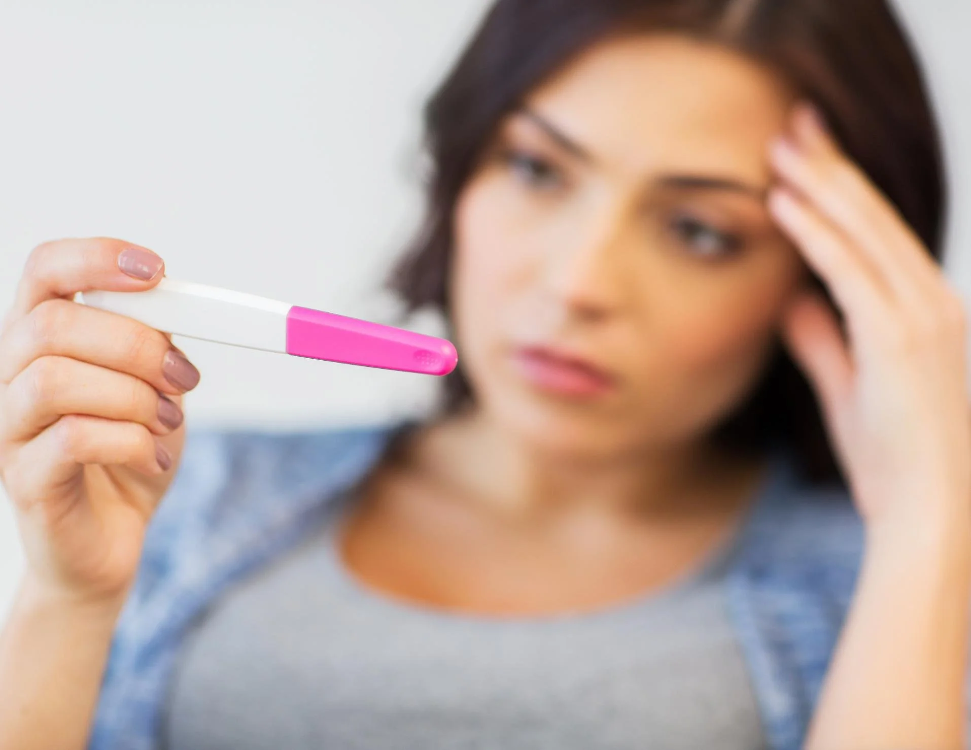 Woman looking at pregnancy test with sad expression