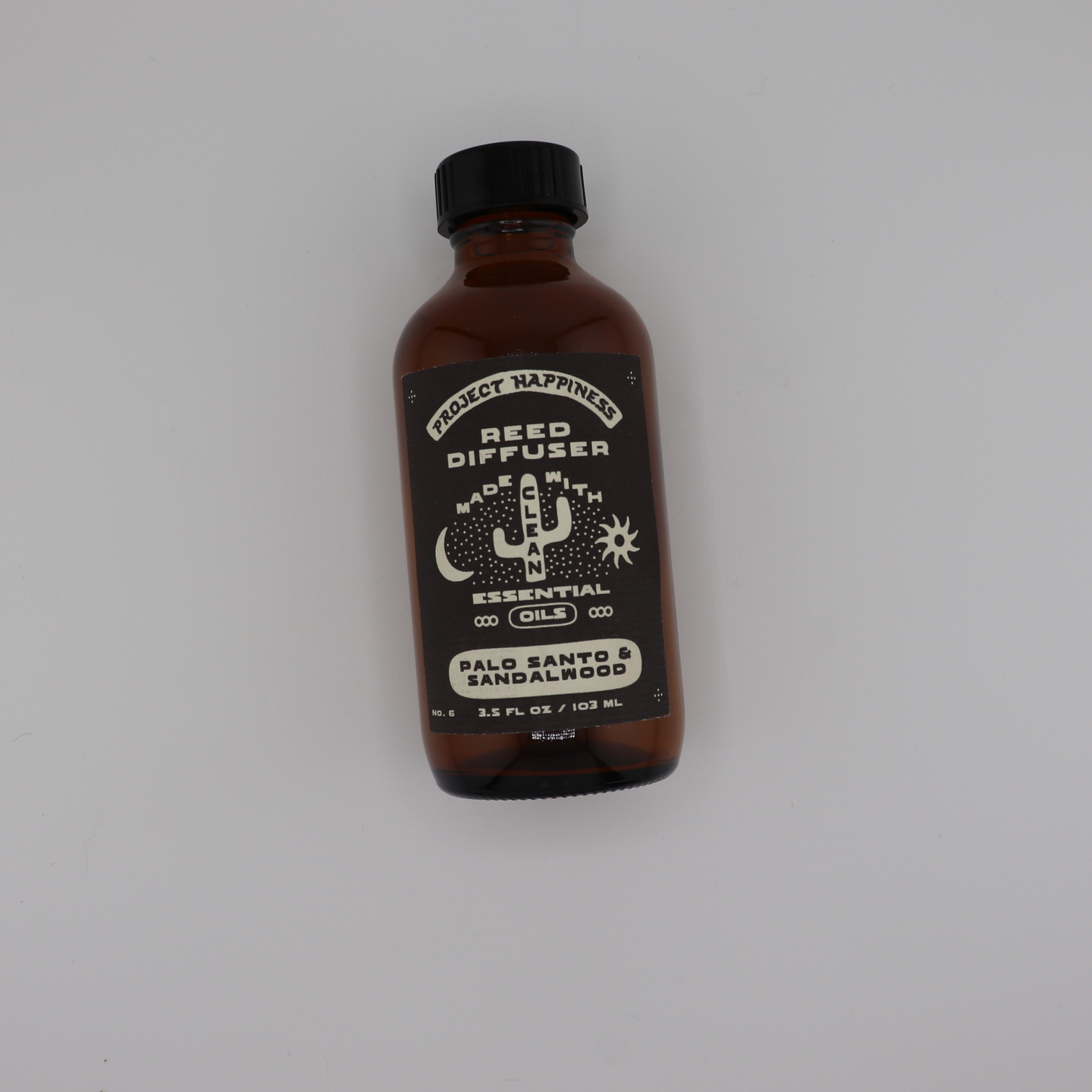 Palo Santo & Sandalwood Reed Diffuser in an amber glass bottle with black reeds, featuring earthy notes of palo santo, sandalwood, patchouli, incense, and moss. Lasts 3–4 months.