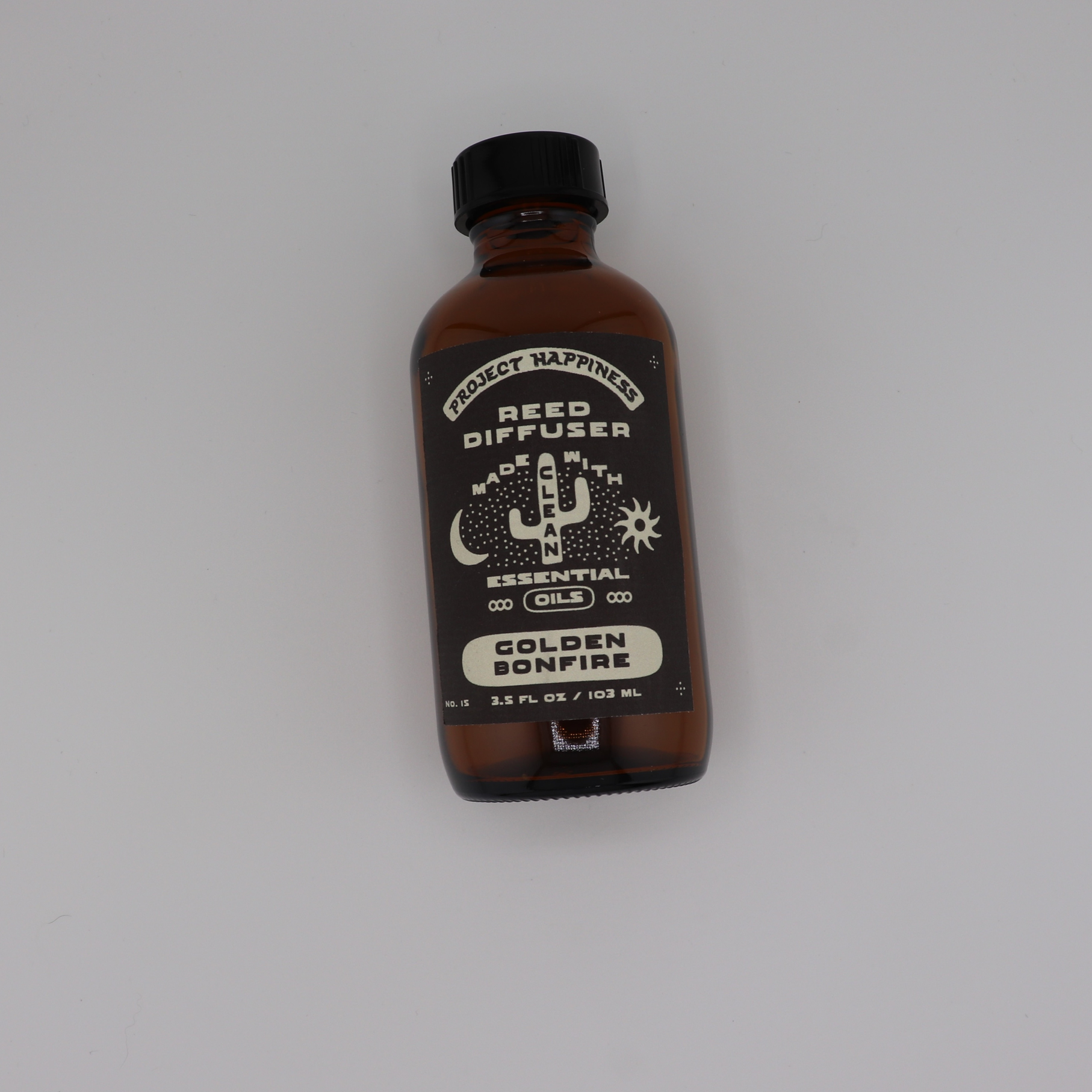 Golden Bonfire Reed Diffuser in an amber glass bottle with black reeds, featuring warm smoky notes of maple, amber, cedar, sandalwood, and musk. Lasts 3–4 months.
