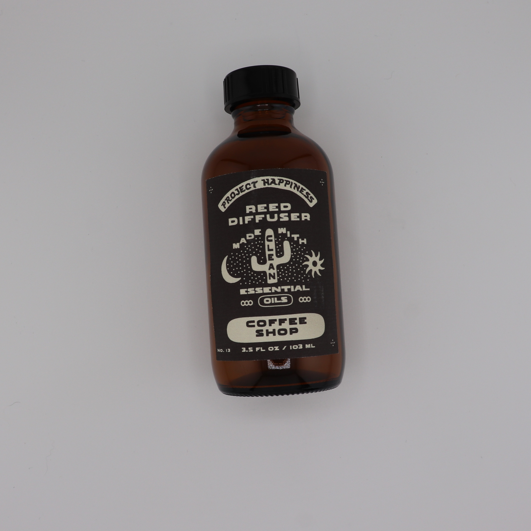 Coffee Shop Reed Diffuser in an amber glass bottle with black reeds, featuring cozy notes of coffee, caramel, sugar, vanilla, and creamy milk. Lasts 3–4 months.