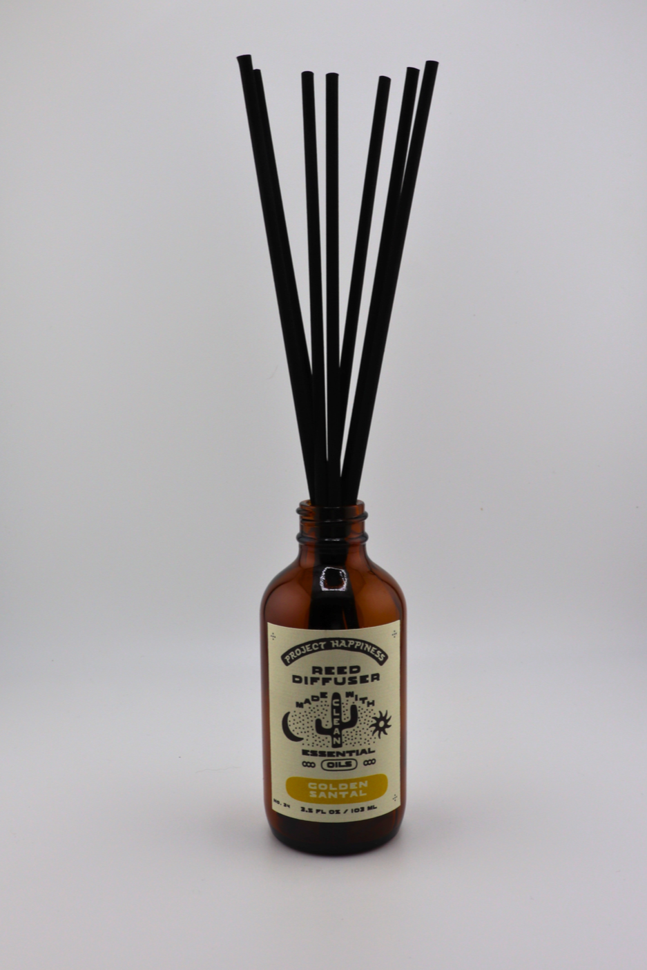 Golden Santal Reed Diffuser in an amber glass bottle with 7 black reeds, featuring herbal notes of fennel, sage, cedar, amber, balsam, and sandalwood. Lasts 3–4 months.