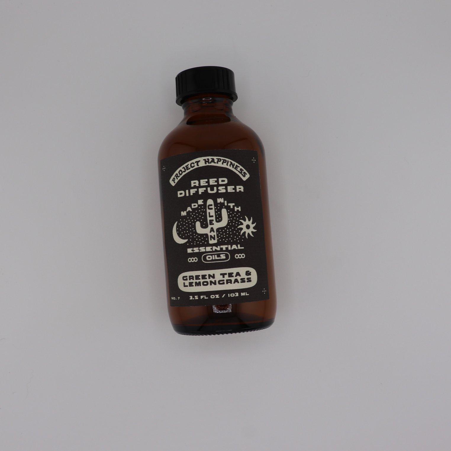 Green Tea & Lemongrass Reed Diffuser in an amber glass bottle with black reeds, featuring fresh notes of lemongrass, green tea, jasmine, citrus, and light musk. Lasts 3–4 months.
