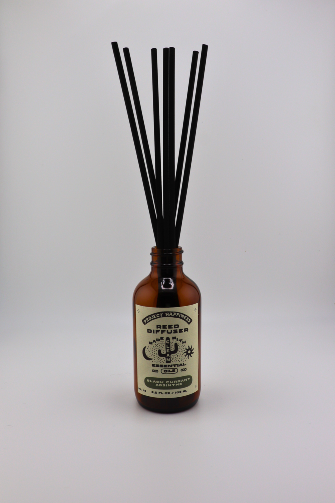 Black Currant Absinthe Reed Diffuser in an amber glass bottle with 7 black reeds, featuring dark notes of black currant, oud, amber, smoke, myrrh, and musk. Lasts 3–4 months.