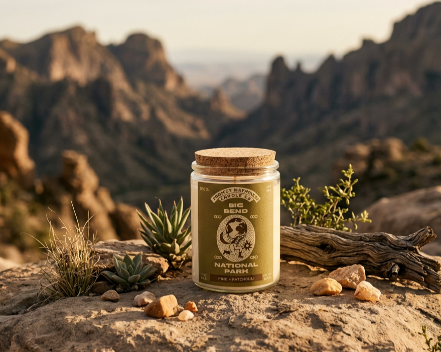 A big bend candle sitting on the dirt ground with the national park in the background