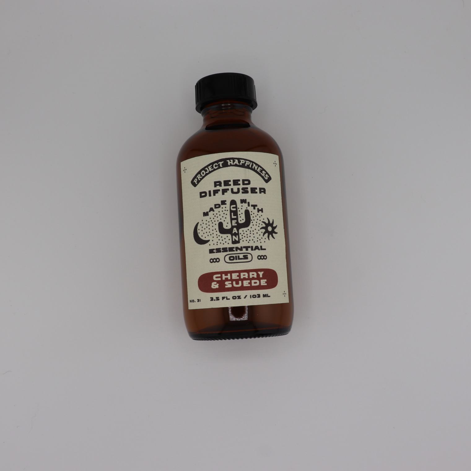 Cherry & Suede Reed Diffuser in an amber glass bottle with black reeds, featuring rich notes of black cherry, vanilla, leather, amber, sandalwood, and incense. Lasts 3–4 months.