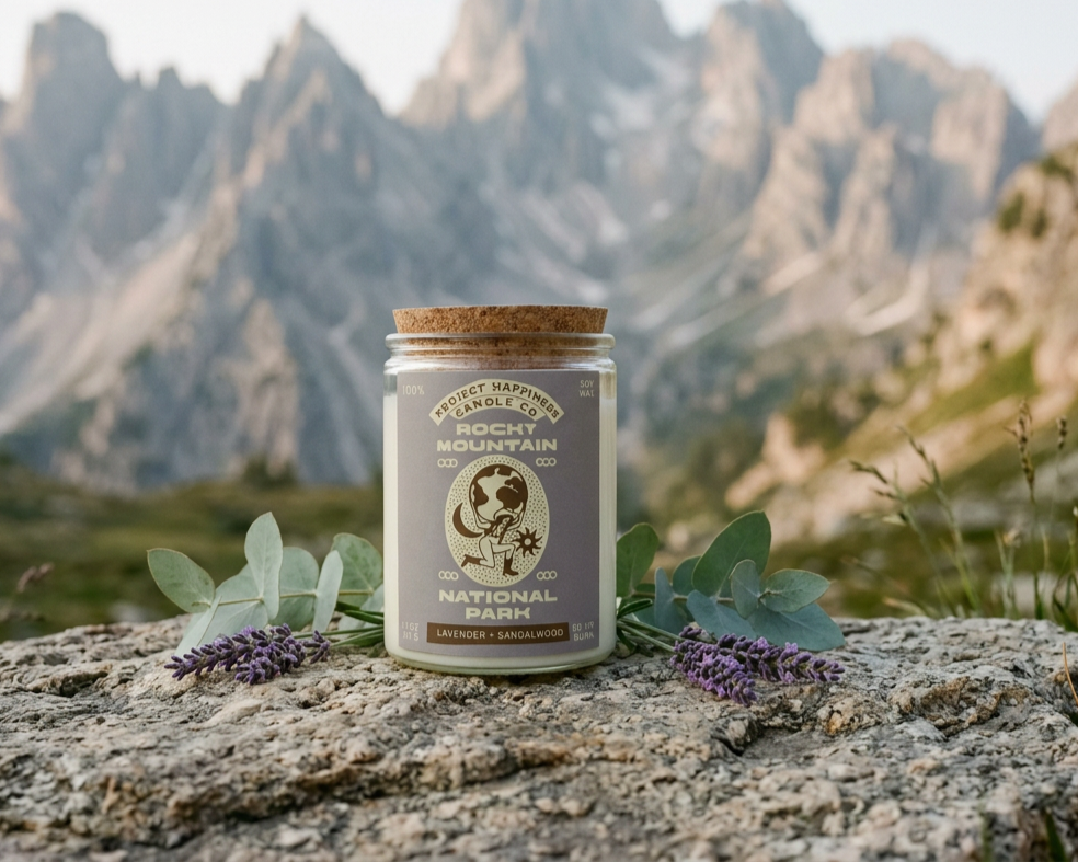 A Rocky Mountain national park candle on top of a rock with  Rocky Mountains in the background
