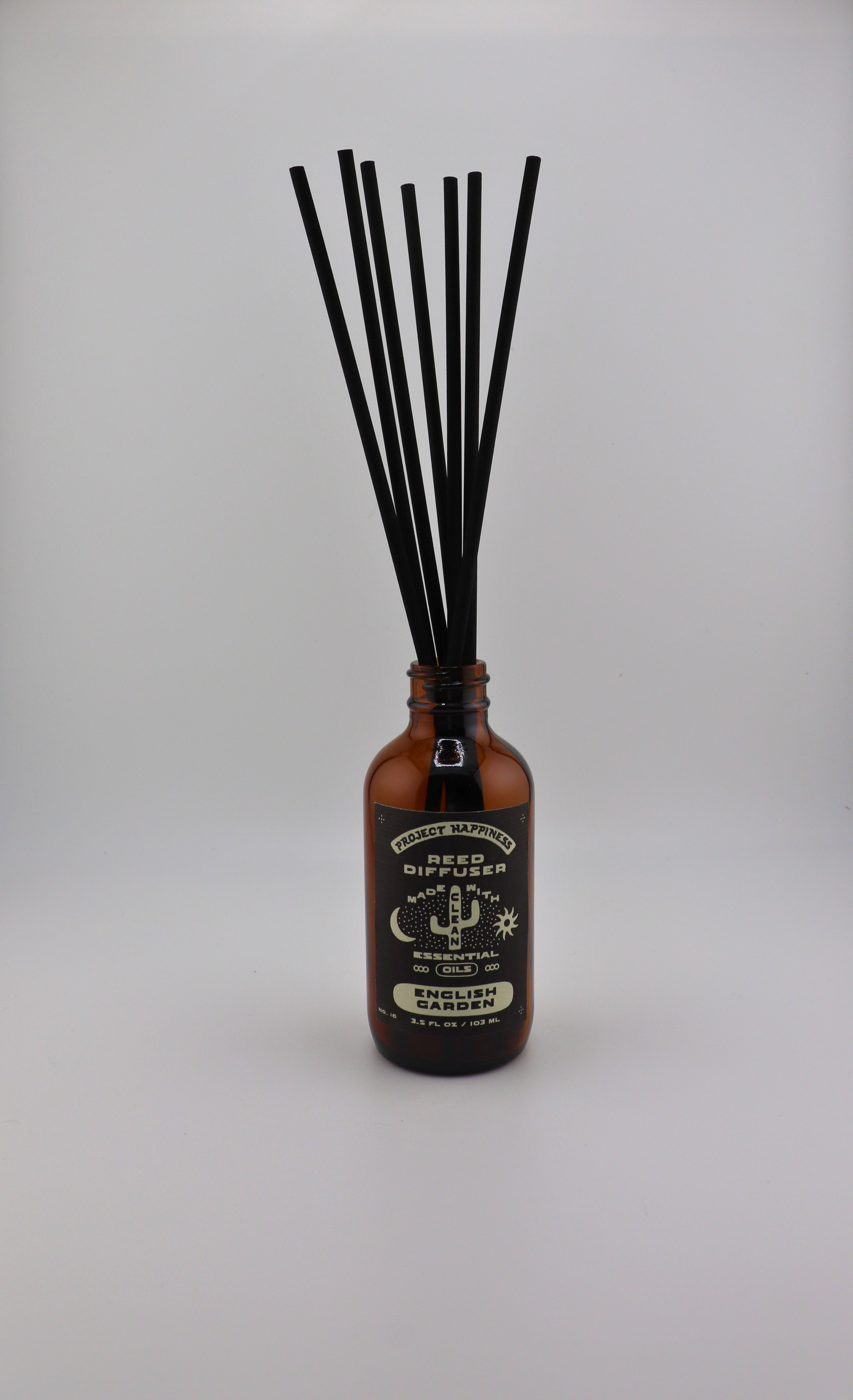 English Garden Reed Diffuser in an amber glass bottle with 7 black reeds, featuring fresh notes of pear, lily of the valley, rose, jasmine, lilac, and vanilla. Lasts 3–4 months.