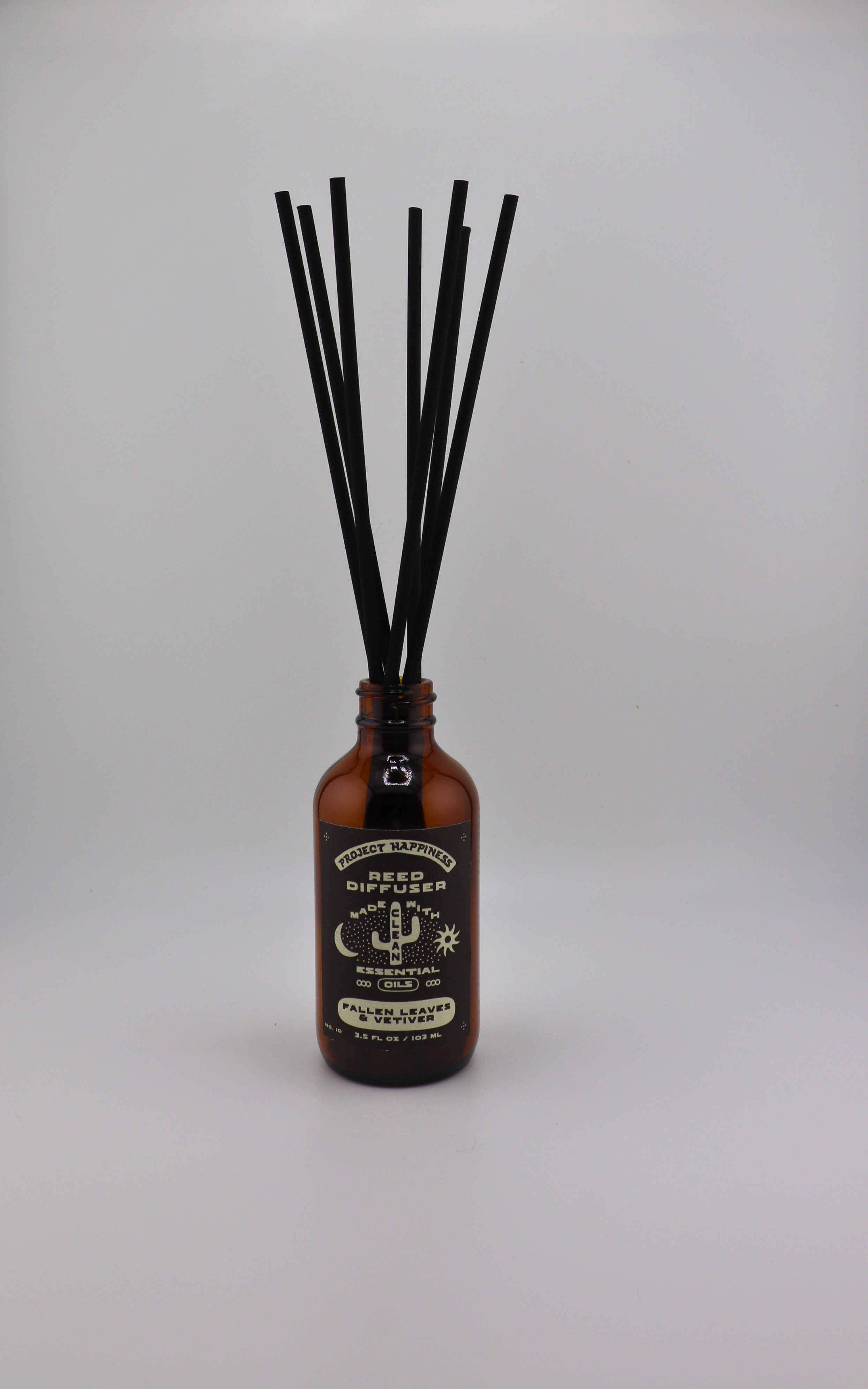 Fallen Leaves & Vetiver Reed Diffuser in an amber glass bottle with 7 black reeds, featuring warm notes of cinnamon, apple, berries, amber, pecan, and vetiver. Lasts 3–4 months.