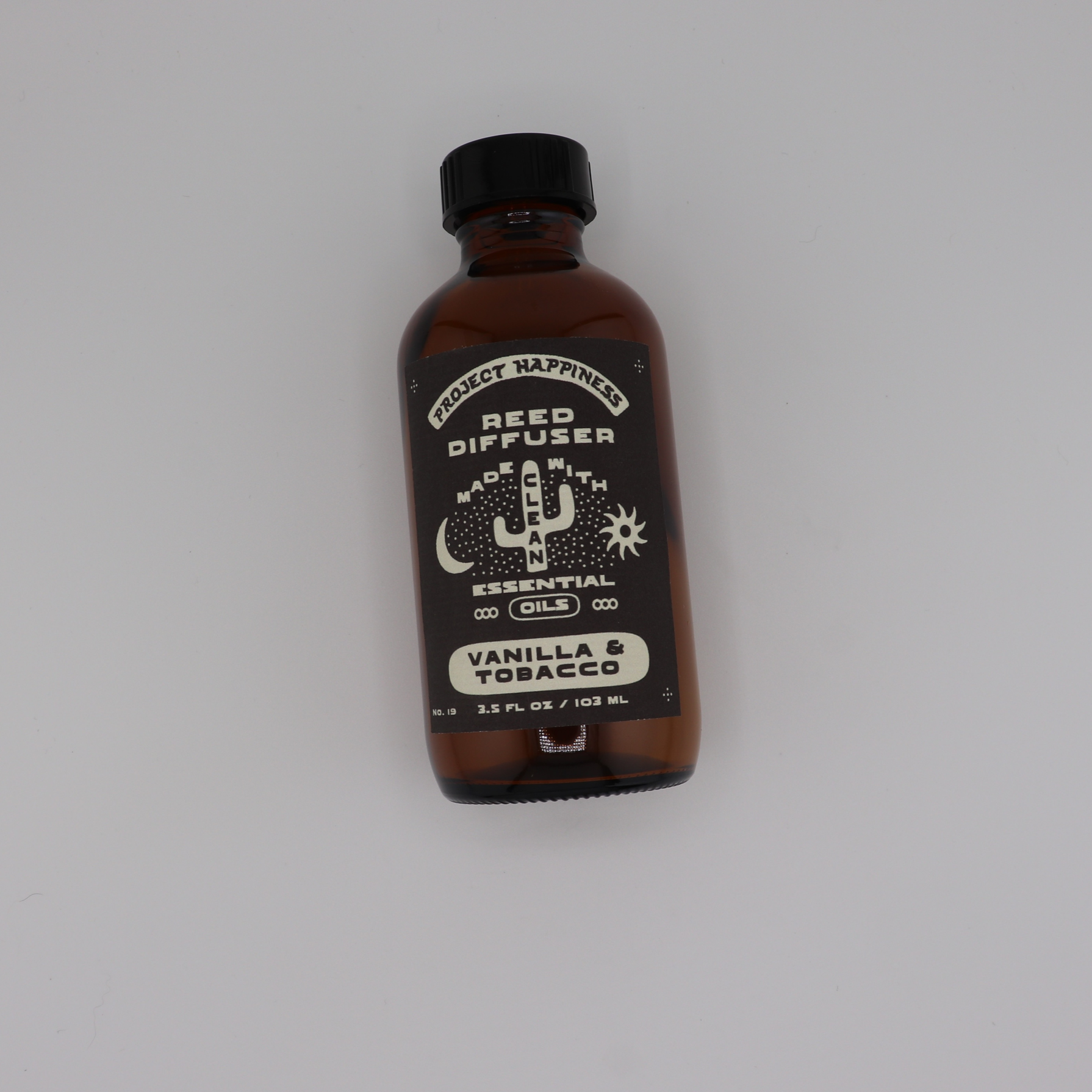 Vanilla & Tobacco Reed Diffuser in an amber glass bottle with black reeds, featuring warm notes of honey, leather, tobacco, whiskey, vanilla, and oak. Lasts 3–4 months.