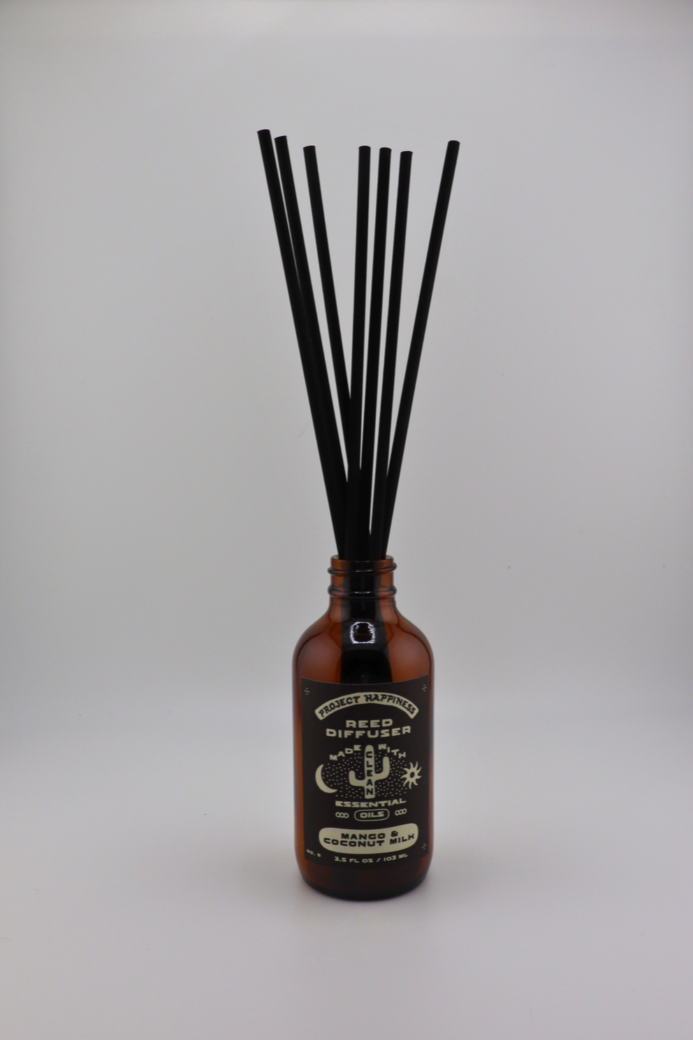 Mango & Coconut Milk Reed Diffuser in an amber glass bottle with 7 black reeds, featuring tropical notes of pineapple, mango, peach, and creamy coconut milk. Lasts 3–4 months.