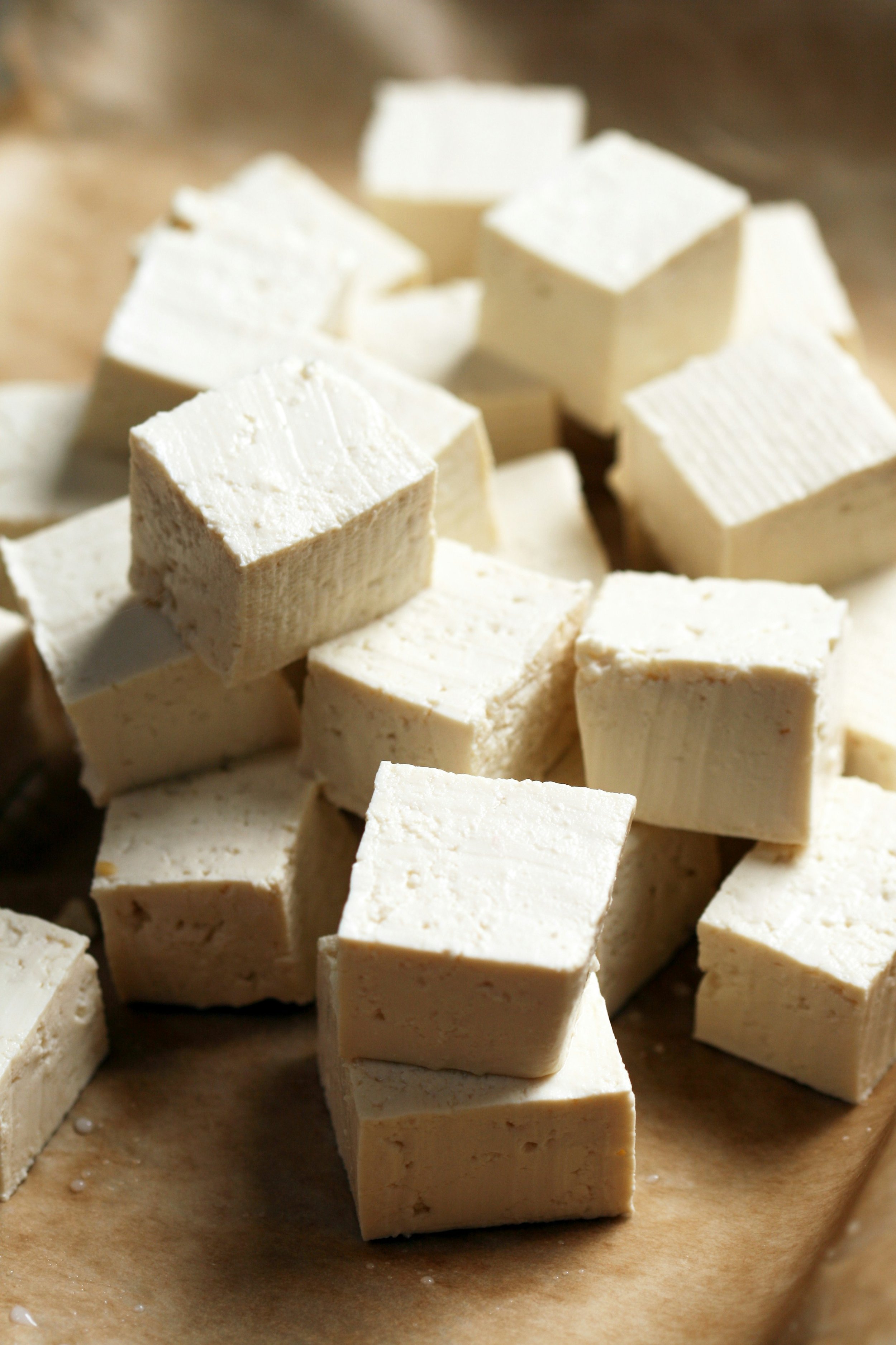 Cubed tofu pieces on a wooden surface.
